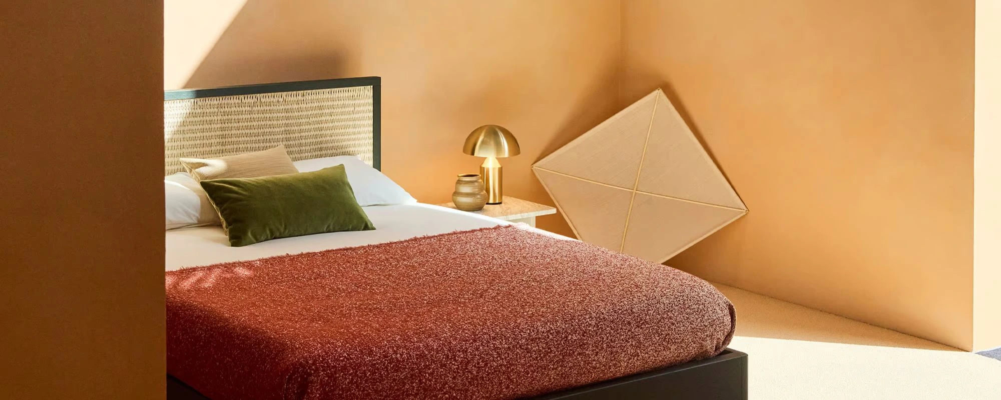 Bedroom with a bed, lamp, and decorative pillows against a beige wall.