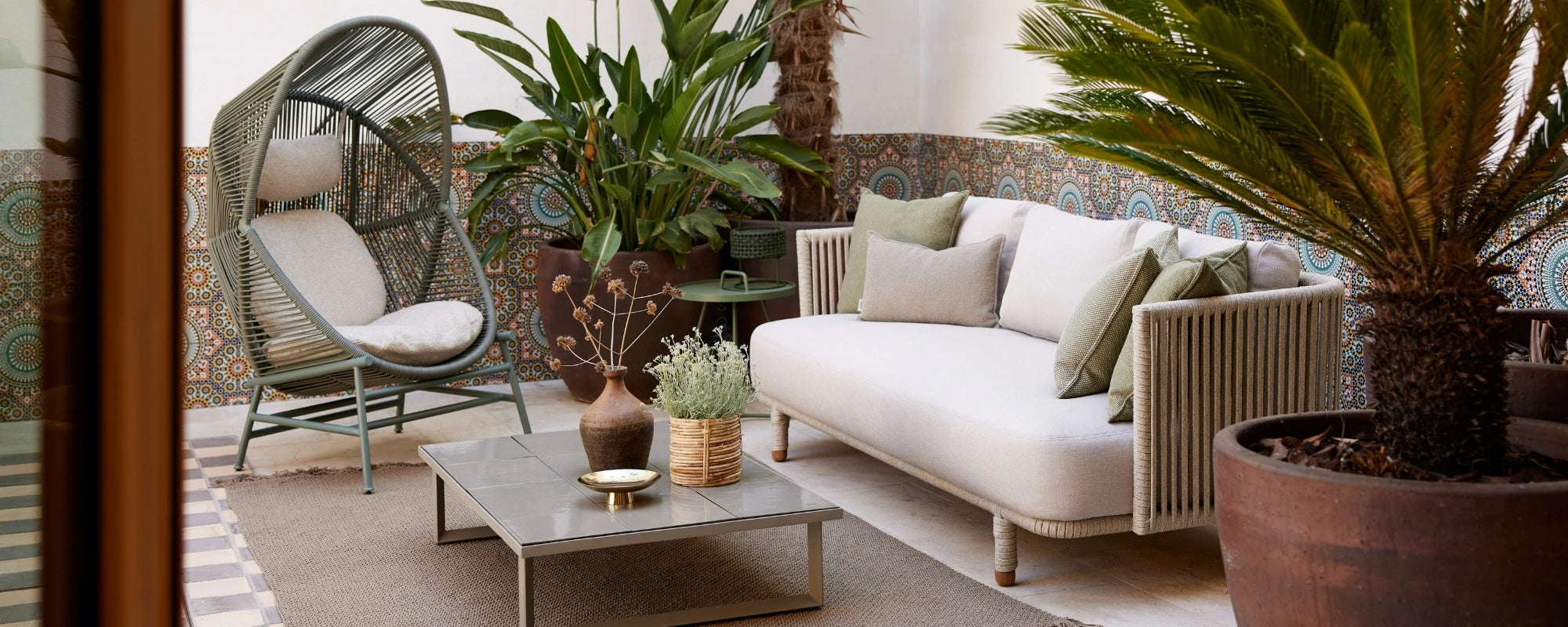 Indoor patio with wicker chair, white sofa, and potted plants